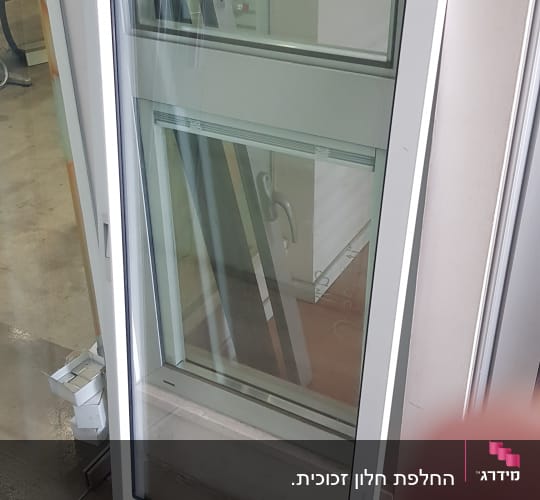 חלון זכוכית עם מסגרת לבנה עומד על הרצפה